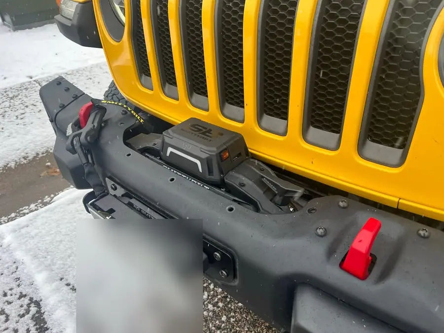 Winch in a steel front bumper on a yellow Jeep Wrangler in the snow
