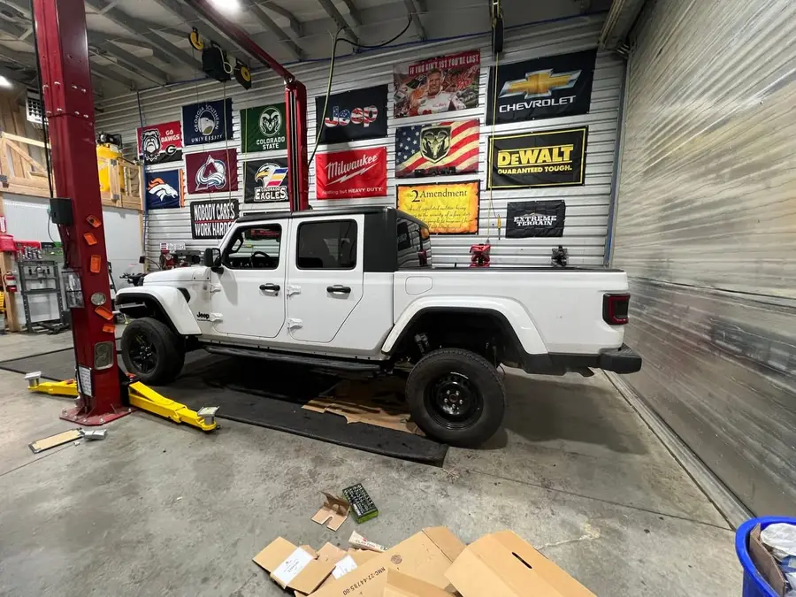 White Jeep Gladiator on a lift inside the Off-Camber shop during an install