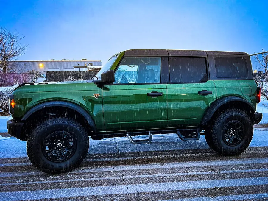 Green Ford Bronco on black wheels and all-terrain tires in the snow