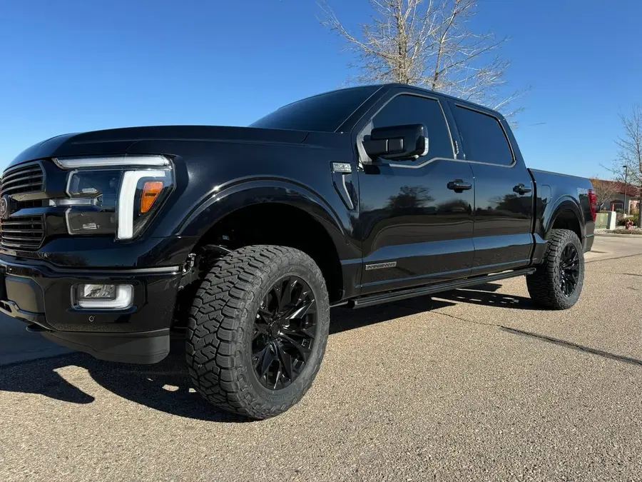 Black Ford F-150 with aftermarket headlights, front three-quarter view