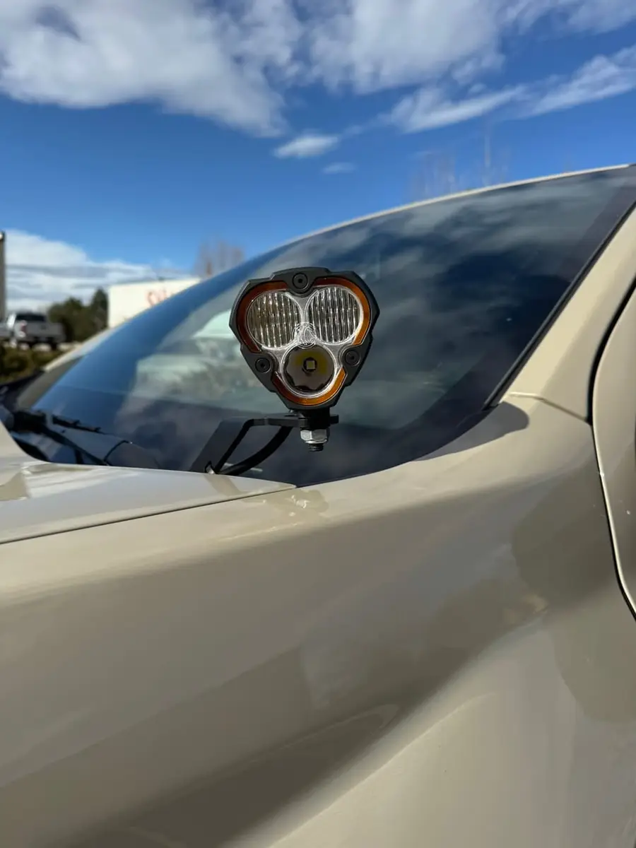 Round pod light mounted at the base of a windshield