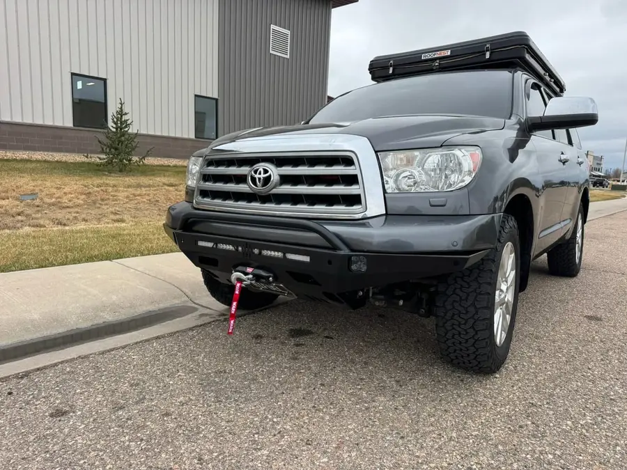 Gray Toyota Tundra with a roof top tent and steel front bumper with winch