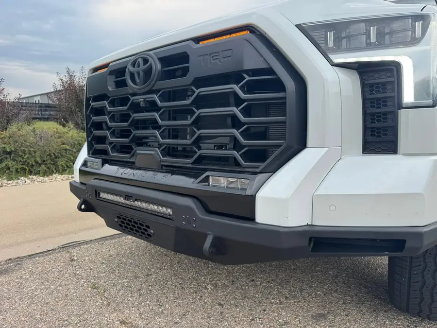 Close-up of a white Toyota Tundra TRD front end fitted with a steel off-road bumper and LED light bar