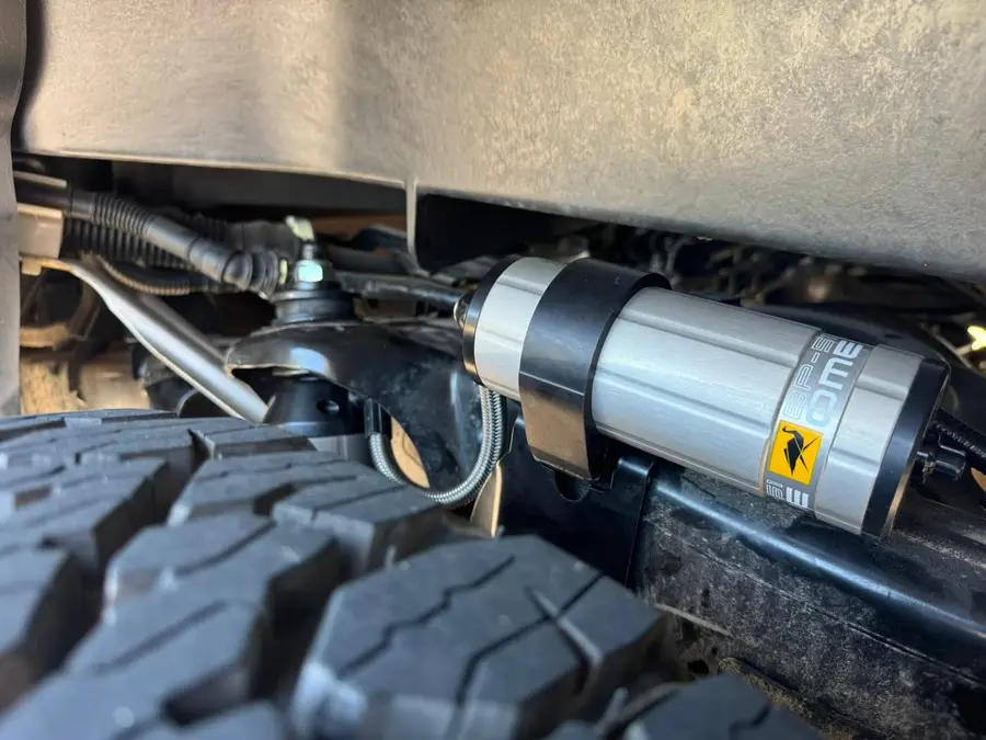 Remote-reservoir shock mounted behind an off-road tire