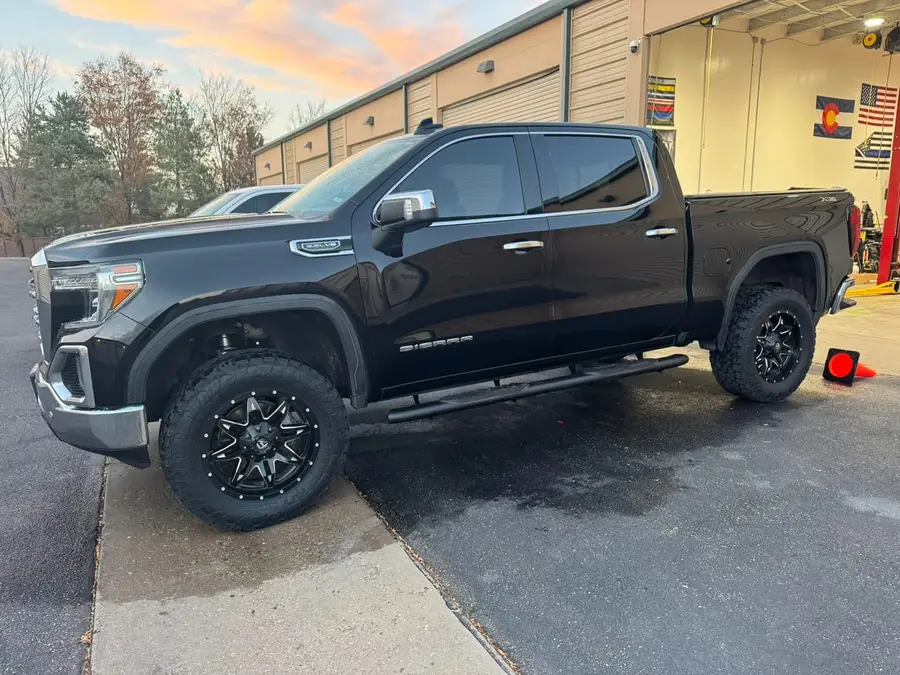 Black GMC Sierra on black aftermarket wheels outside the shop