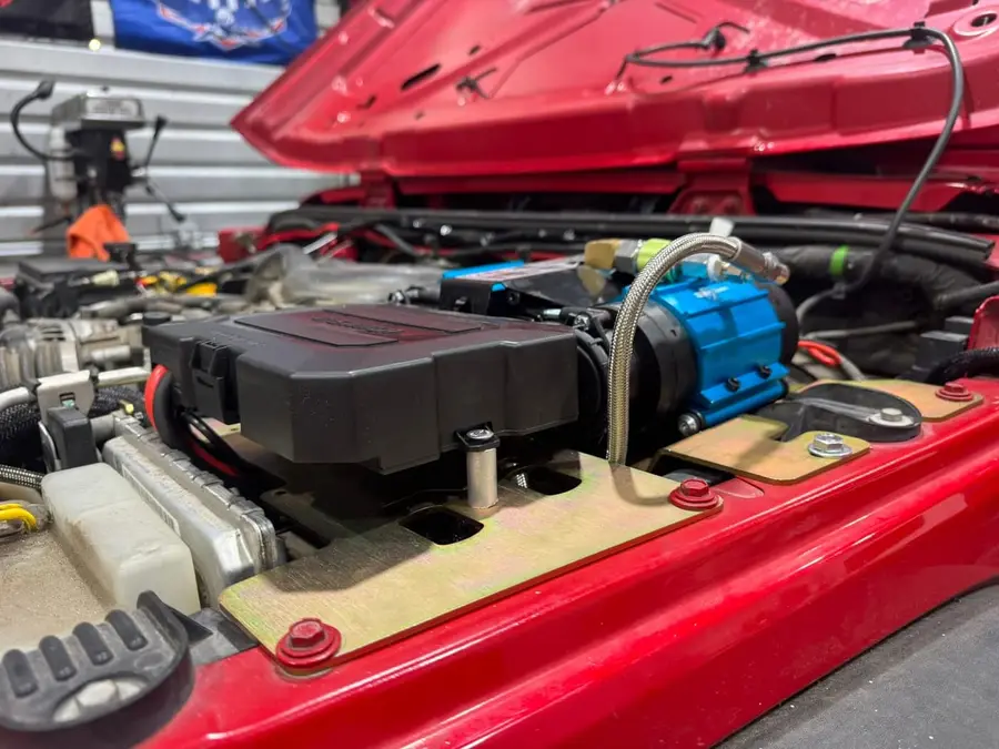 Onboard air compressor mounted under the hood of a red Jeep