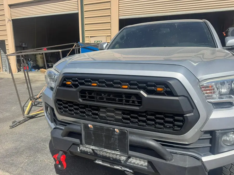 Silver Toyota Tacoma with an aftermarket grille and front bumper with light bar