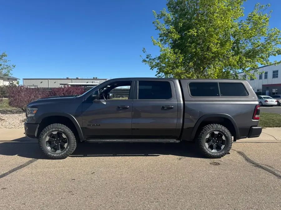 Gray Ram 1500 with a camper shell, side view