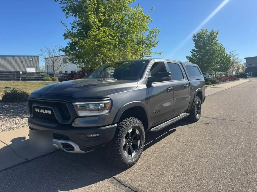Gray Ram 1500 with a camper shell, front three-quarter view