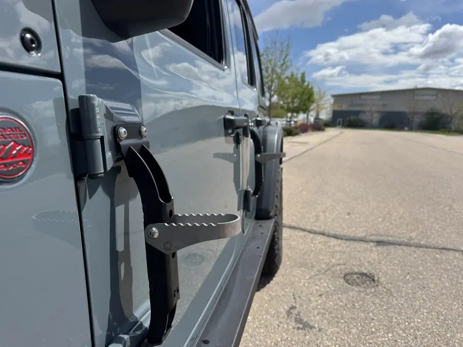 Adventure Rack Systems folding step mounted at the door hinge of a Jeep Wrangler