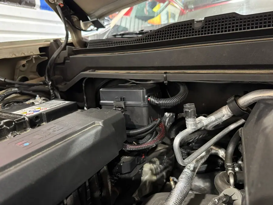 Auxbeam relay box and loomed wiring tucked at the back of a Chevy Colorado engine compartment