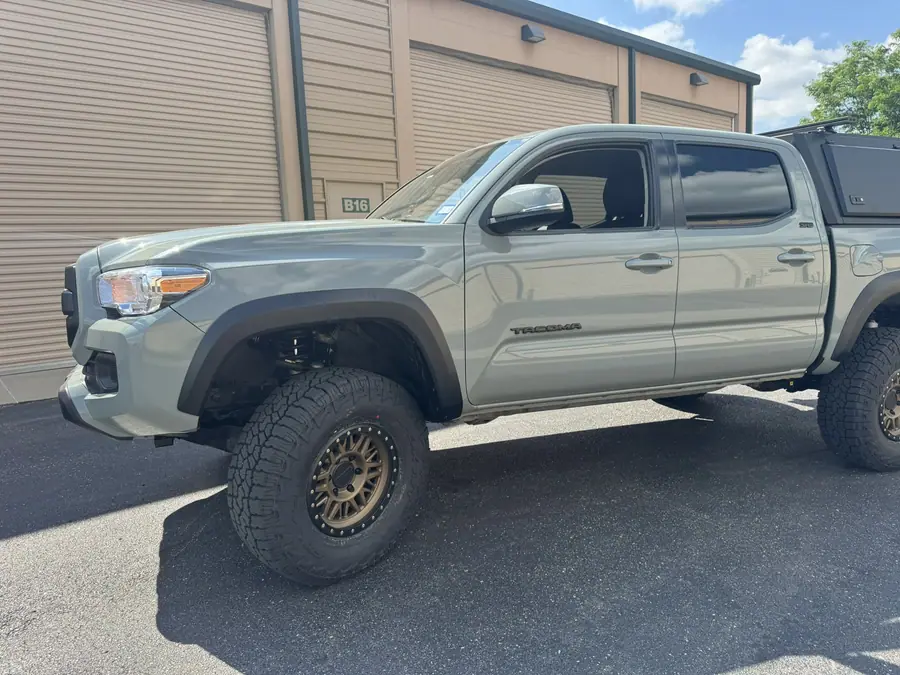 Lifted 2023 Toyota Tacoma with bronze wheels and all-terrain tires, front three-quarter view