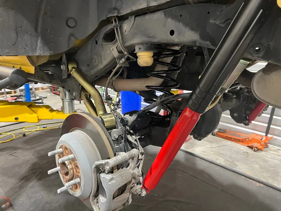 Red MetalCloak RockSport shock installed at the front axle of a Jeep Wrangler JL