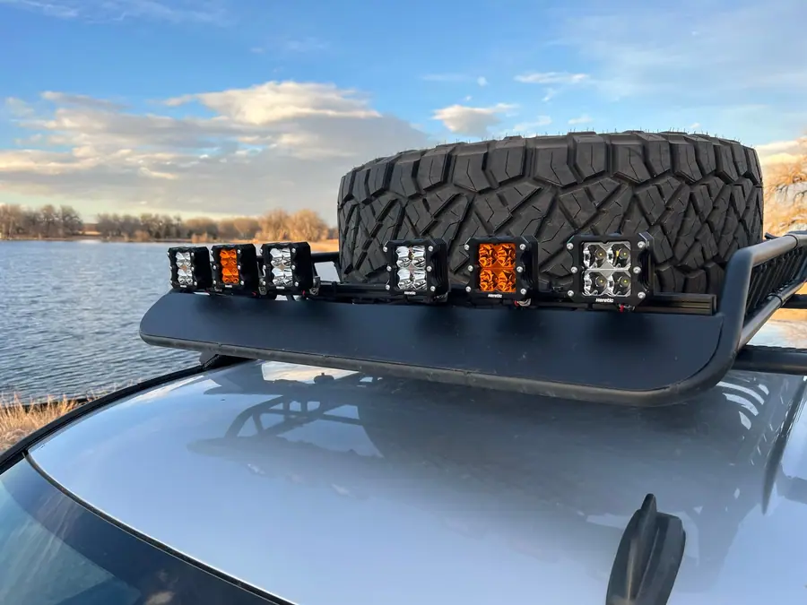 Custom bar holding evenly spaced LED pods on a truck roof basket