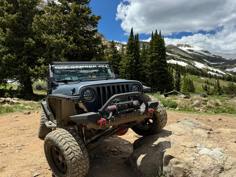 Off-Camber Jeep on rocks with snowy peaks behind