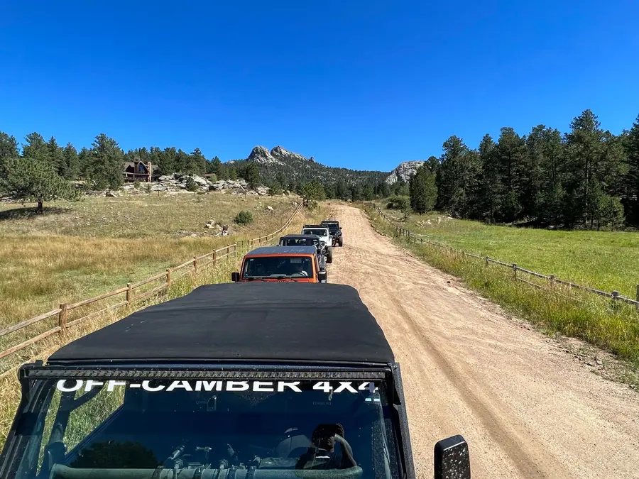 Club convoy on a dirt road seen past the Off-Camber 4x4 windshield banner