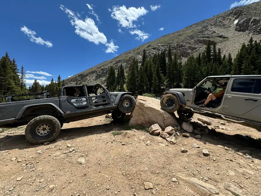 Jeep Gladiator and Wrangler working up a rocky ledge above treeline