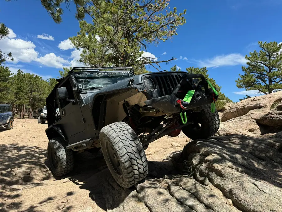 Jeep flexing a front tire up a granite step
