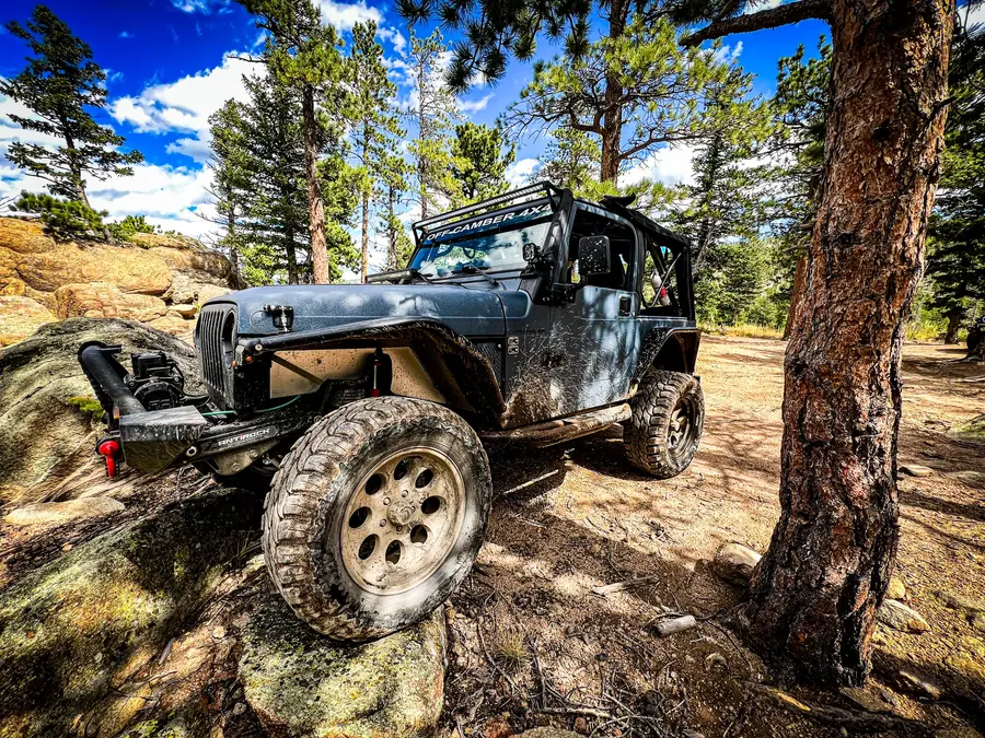 Jeep Wrangler JK crawling past a boulder in the pines