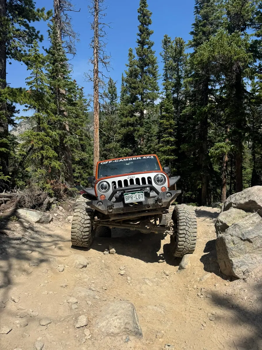 Jeep Wrangler crawling between boulders in the pines