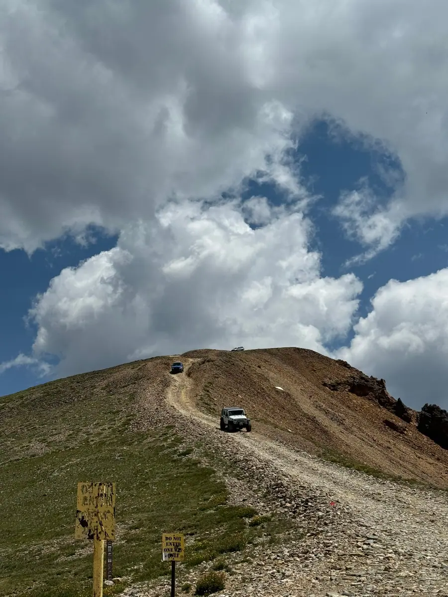 Jeep climbing a steep mountain road toward the summit
