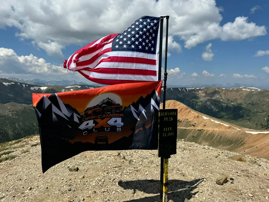 American flag and Off-Camber 4x4 Club flag on a Colorado summit