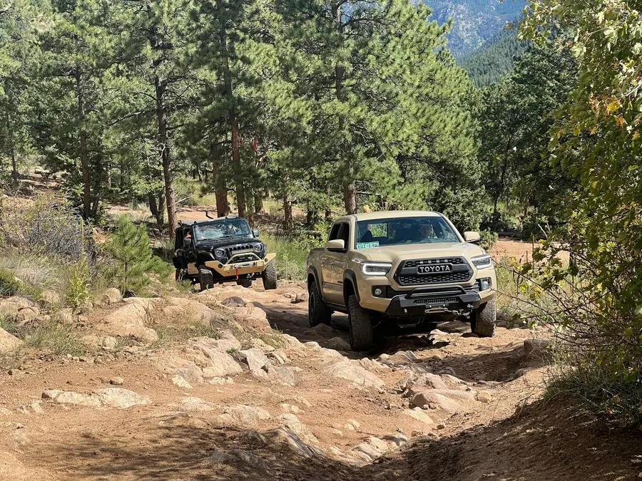 Toyota Tacoma and Jeep working through a rocky forest trail