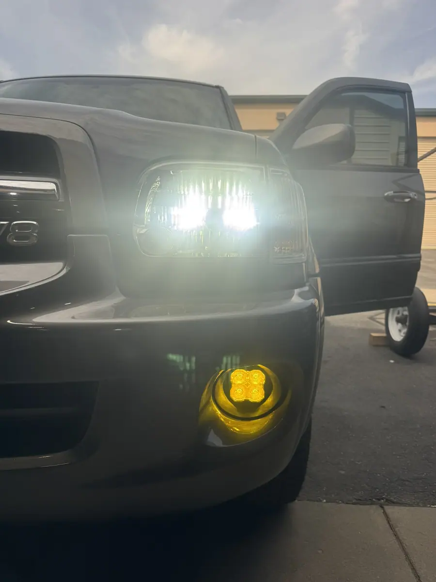 Diode Dynamics SS3 SAE yellow LED fog light lit in the factory fog location of a pickup