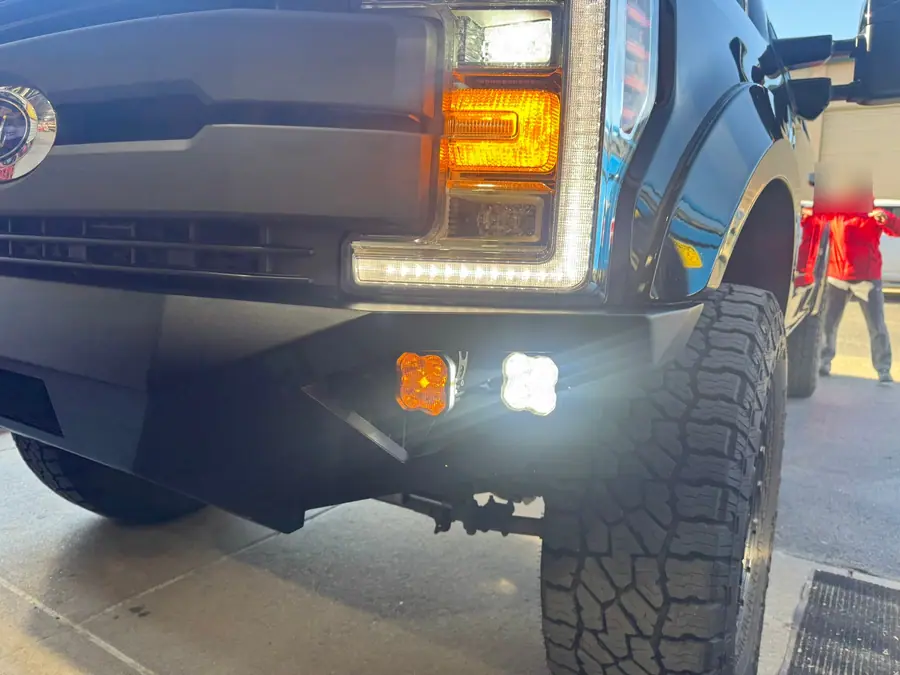 Amber and white LED pods lit in the front bumper of a Ford Super Duty