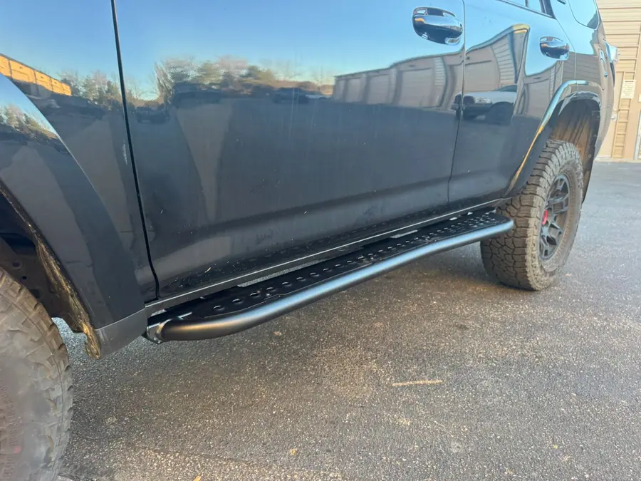 RCI Off Road rock sliders with a perforated step plate installed on a black 2022 Toyota 4Runner