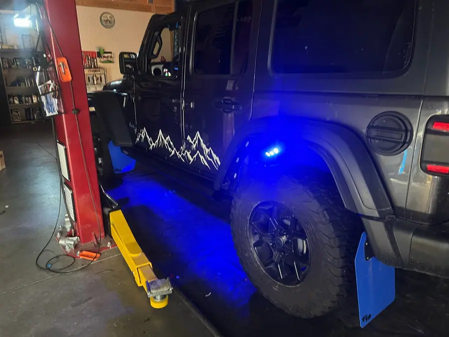 Rock lights glowing under the wheel wells of a Jeep Wrangler