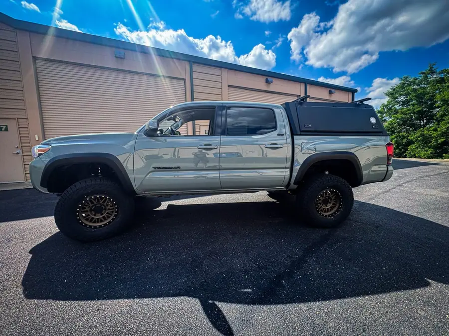 Lifted Toyota Tacoma with a hard-shell bed cap and roof bars