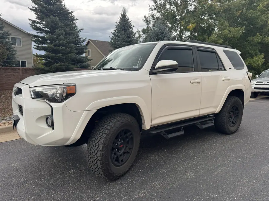 White 5th gen Toyota 4Runner with a leveling kit, black wheels, all-terrain tires and running boards