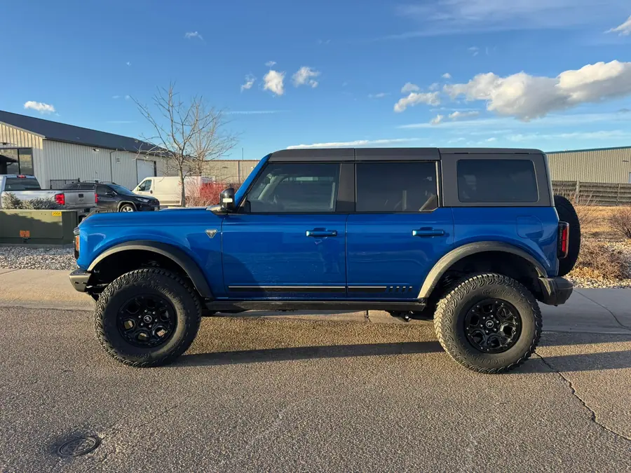 Blue lifted four-door Ford Bronco on all-terrain tires