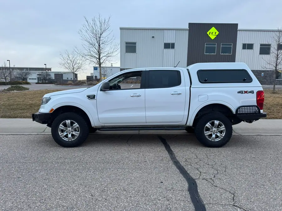 White lifted Ford Ranger with a camper shell