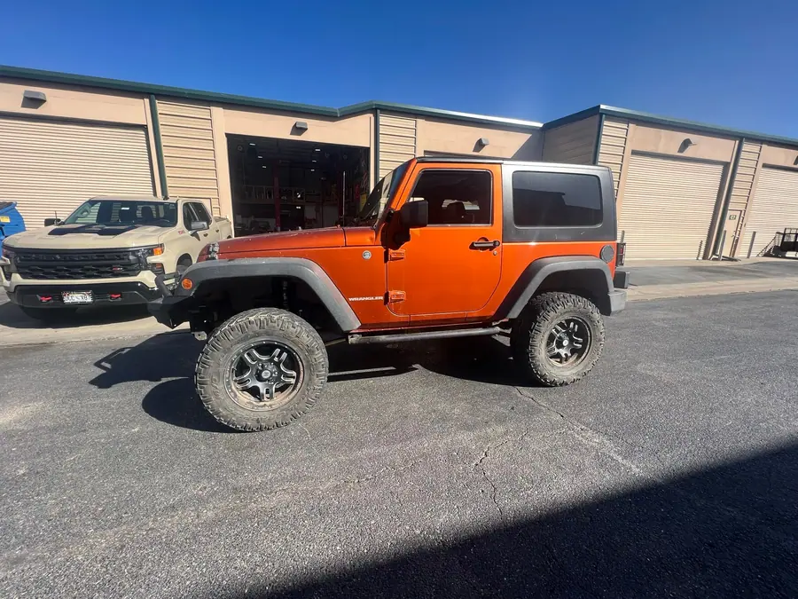 Orange lifted two-door Jeep Wrangler JK on mud-terrain tires
