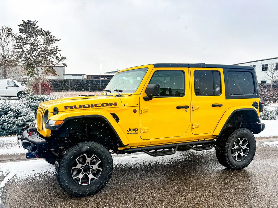 Yellow lifted Jeep Wrangler JL Rubicon four-door on all-terrain tires