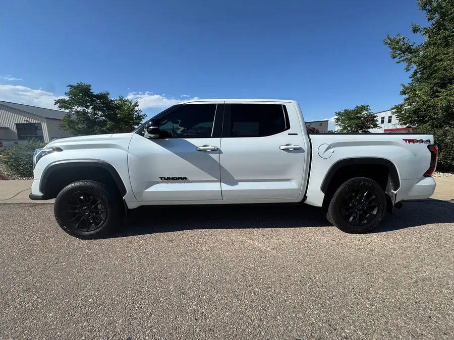 White Toyota Tundra on black wheels and all-terrain tires